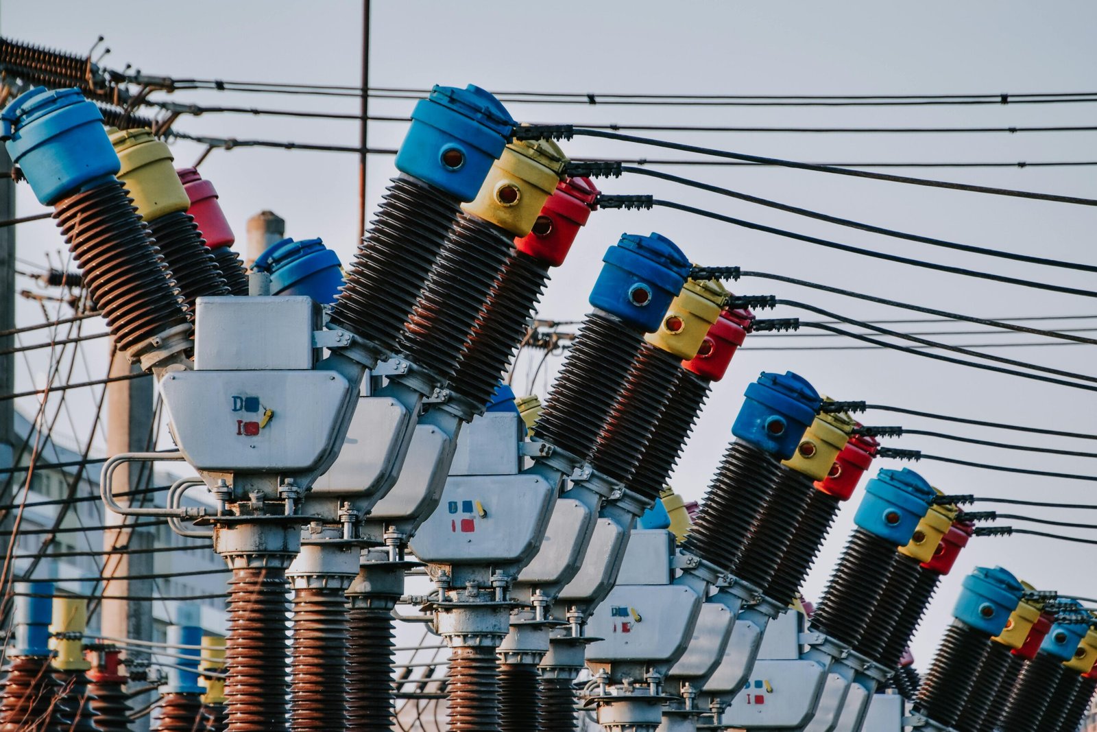 Close-up of electrical transformers with colorful tops and wires in an outdoor setting.